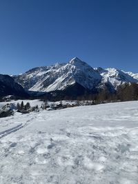 Scenic view of snowcapped mountains against clear blue sky