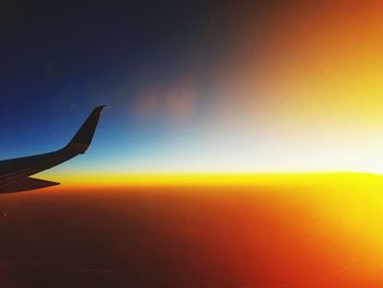 Close-up of airplane flying over sea at sunset