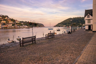 Man sitting on bench at riverbank during sunset