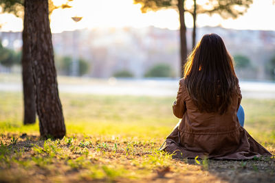 Rear view of woman sitting on land