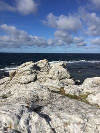 View of rocky beach against cloudy sky