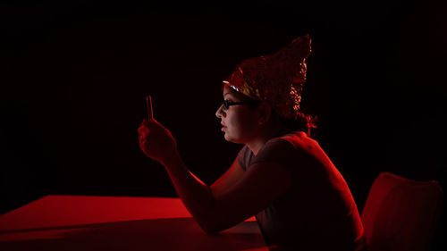 Rear view of young woman sitting against black background