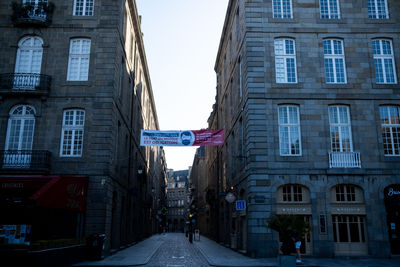 Road amidst buildings in city against sky