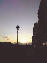 Silhouette lamp post against sky at dusk