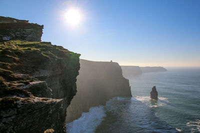 Scenic view of sea by cliff against sky