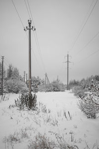 Electricity pylon on field against clear sky during winter