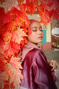 Close-up of senior woman standing with autumn leaves