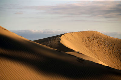 Sand dunes in desert against sky