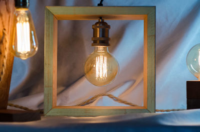 Close-up of illuminated light bulb on wall at home