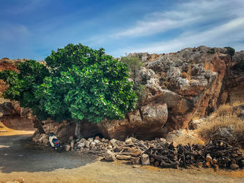 Rock formation by tree against sky with a scooter under tree 