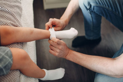 Low section of father covering daughter leg with sock