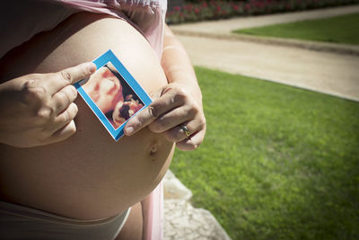 Seven month pregnant woman with ultrasound of baby on her gut. pink dress color