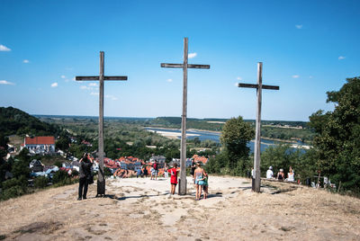 People standing by crosses against blue sky at wlodawa