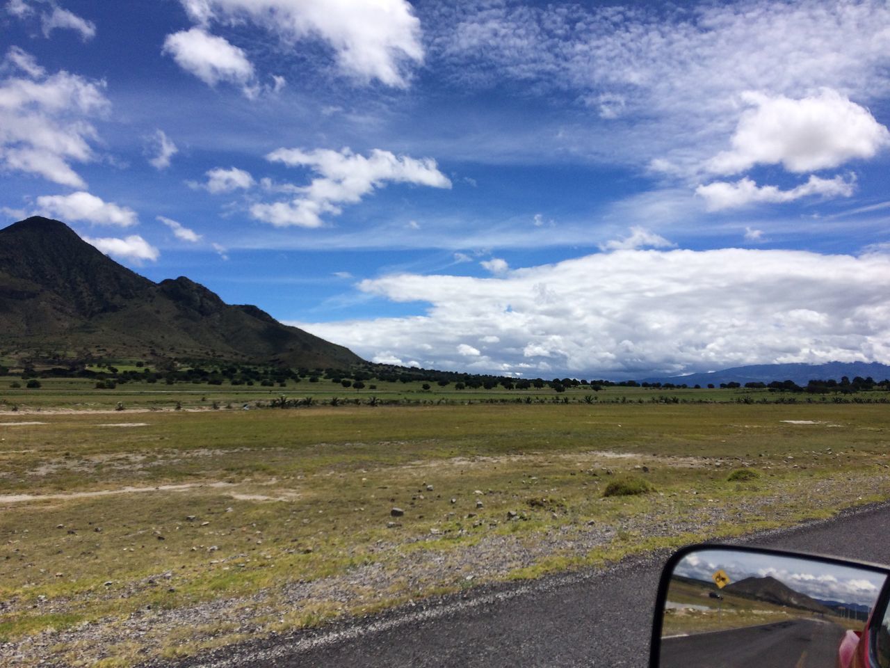 transportation, mode of transport, car, sky, land vehicle, travel, part of, cropped, cloud - sky, cloud, day, scenics, mountain, outdoors, blue, car point of view, non-urban scene, tranquil scene, rural scene, tranquility, beauty in nature, no people