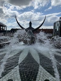 Fountain in front of building against sky