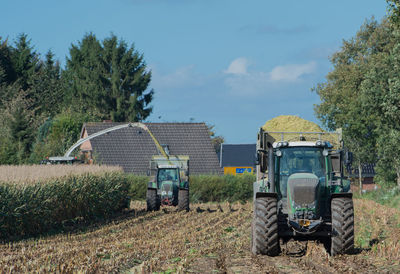 Corn harvest, corn forage harvester in action, harvest truck with tractor