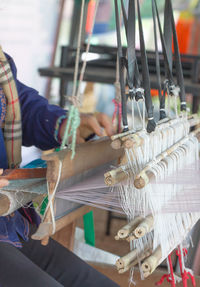 Midsection of woman working with loom in workshop