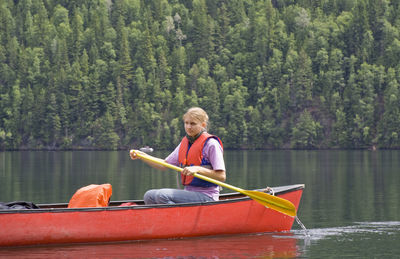 Young woman looking away while canoeing on lake