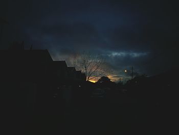 Silhouette of illuminated buildings against sky at night