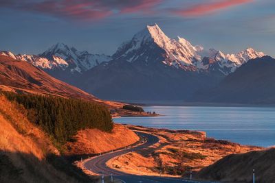 Scenic view of lake by mountains against sky during sunset