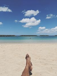 Low section of man at beach against sky