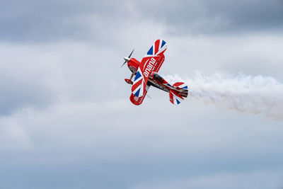 Low angle view of red airplane flying in sky