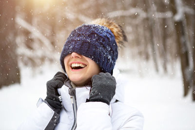 A woman with a warm knitted hat pulled over her eyes smiles and enjoys the snow, the spring 
