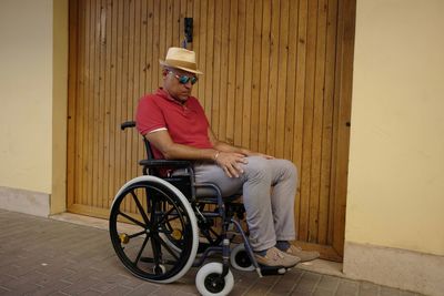Man sitting on wheelchair on footpath