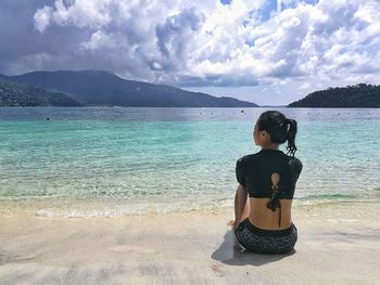 Young woman standing on beach against sky