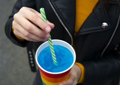 Mixing a blue cocktail with a colorful straw.