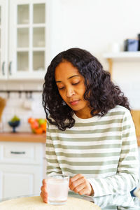 Exhausted african-american woman waiting for fizz pill to dissolve in glass of water in kitchen