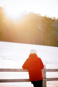 Rear view of woman standing on snow covered landscape