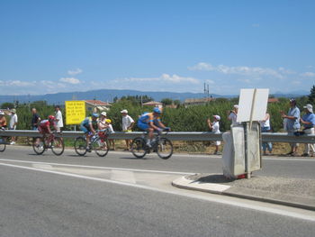 People riding bicycles on road against sky