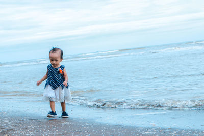 Boy standing on beach against sky