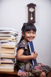 Portrait of a smiling young woman sitting on book