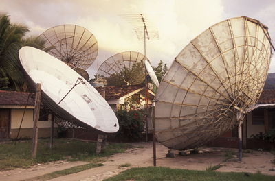 Low angle view of satellite dishes on field against sky