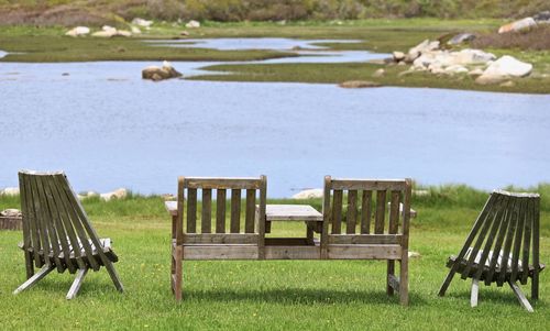 Empty chairs on bench by lake