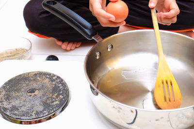 Low section of woman preparing egg in pan