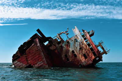 Abandoned ship in sea against sky