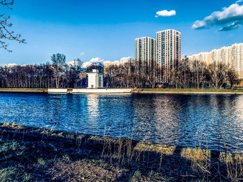 Scenic view of lake by buildings against blue sky