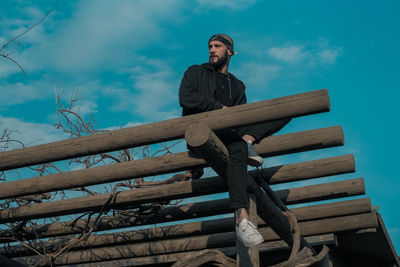 Low angle view of young man looking away against sky