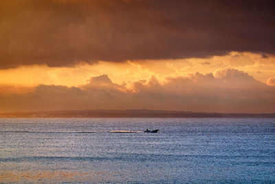 Scenic view of sea against moody sky during sunrise