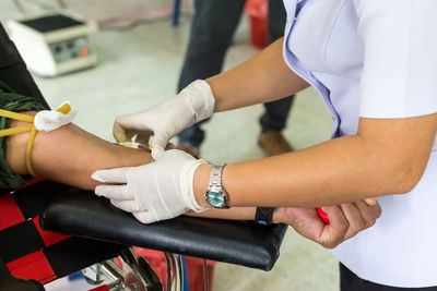 Midsection of nurse taking blood from patient in hospital