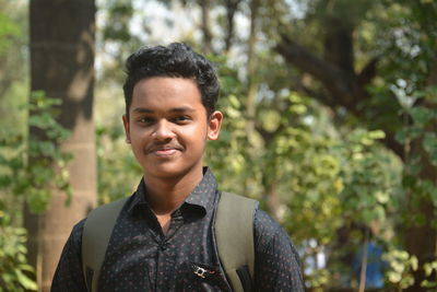 Portrait of young man standing against trees