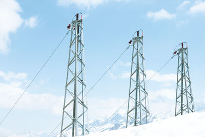 Low angle view of snow covered cranes against sky