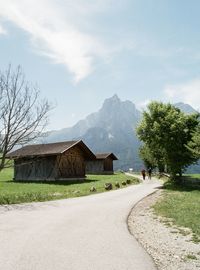 Road by houses and buildings against sky