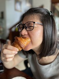 Asianwoman eating croissant