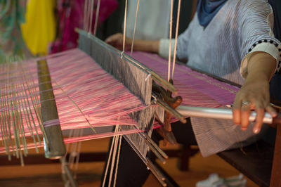 Midsection of woman weaving loom