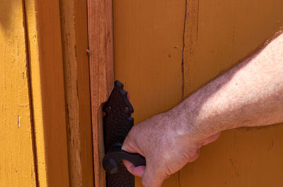 Close-up of man hand on yellow door