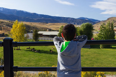 Rear view of man on field against sky